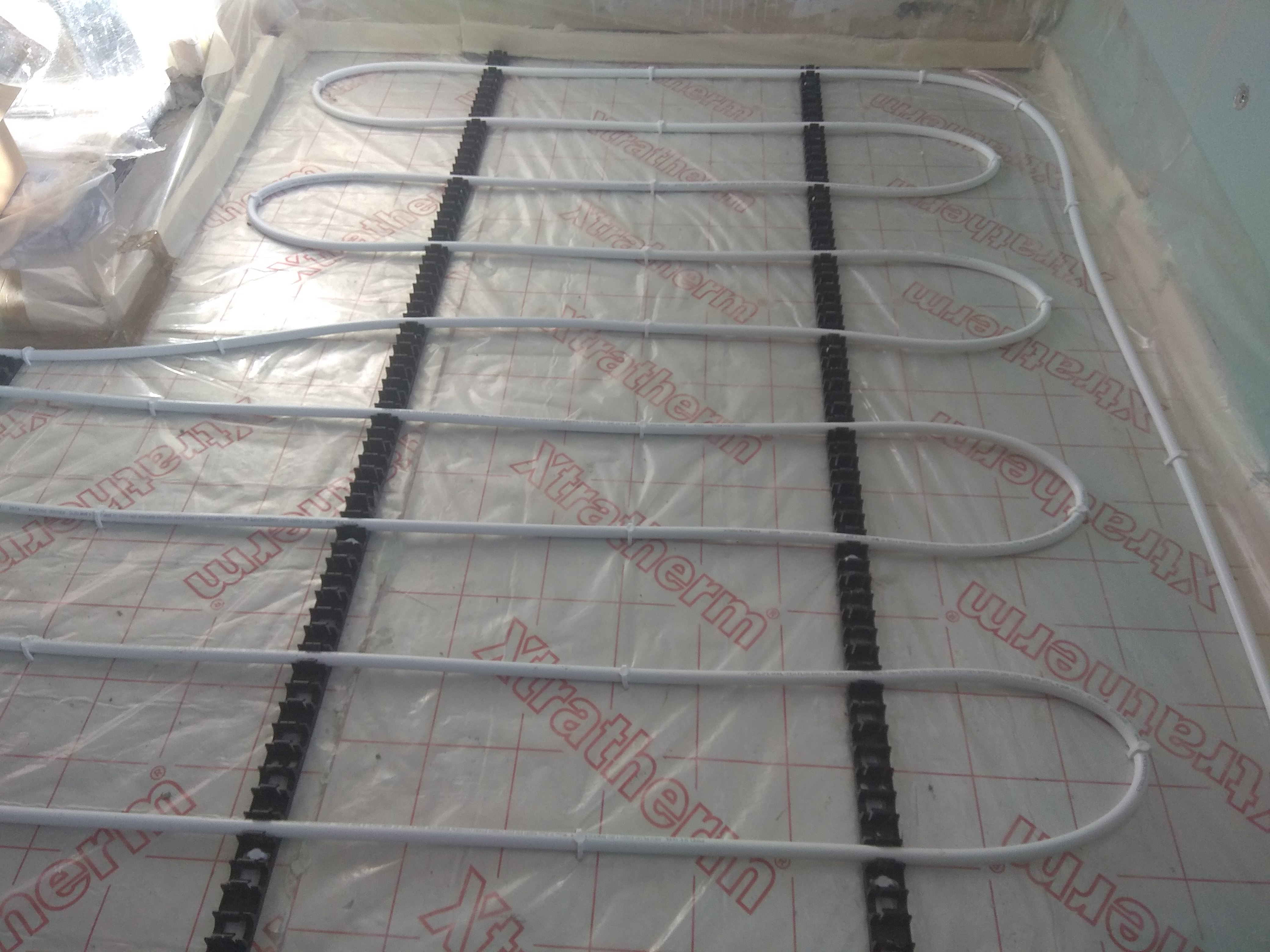 Underfloor heating is surprisingly simple - basically, put down insulation, put down a big loop of pipes and pour two inches of concrete on top